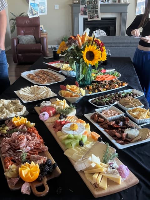A grazing-style spread Lisa and Harrison built for a recent event — charcuterie, cheeses, fresh fruit, and a sunflower centerpiece